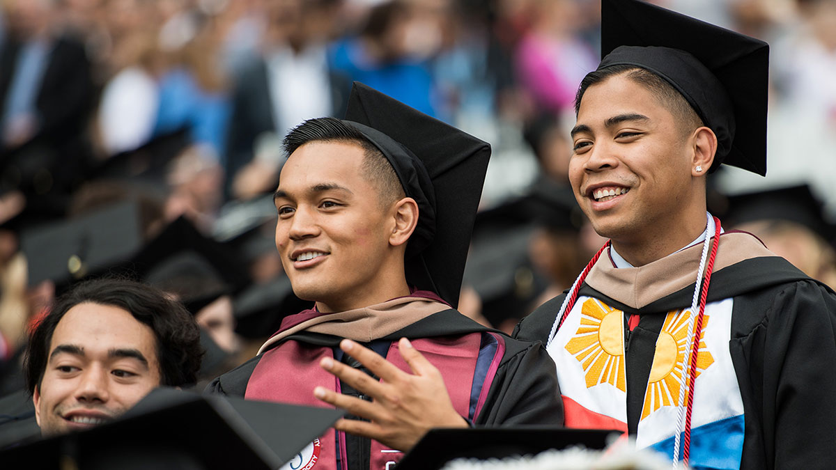 Graduates standing and cheering upon the completion of commencement