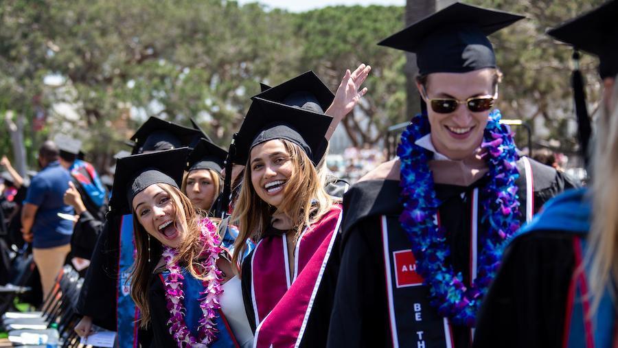Excited graduates standing next to their seats
