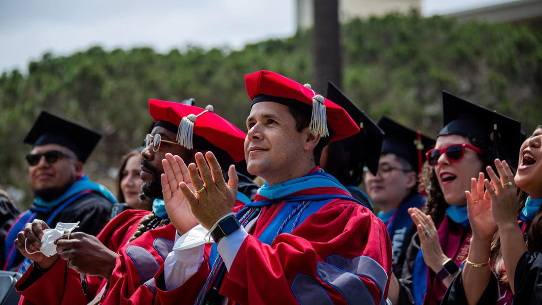 Several doctoral graduates applauding at commencement