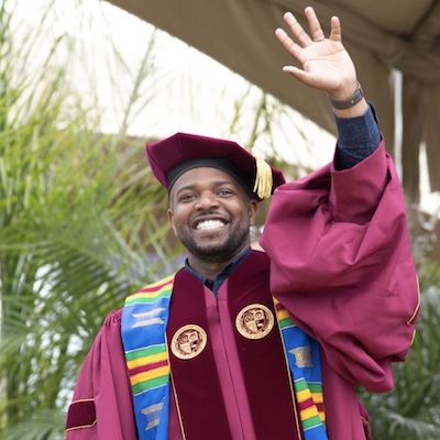 Black male doctoral graduate waving
