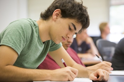 Male student writing in classroom